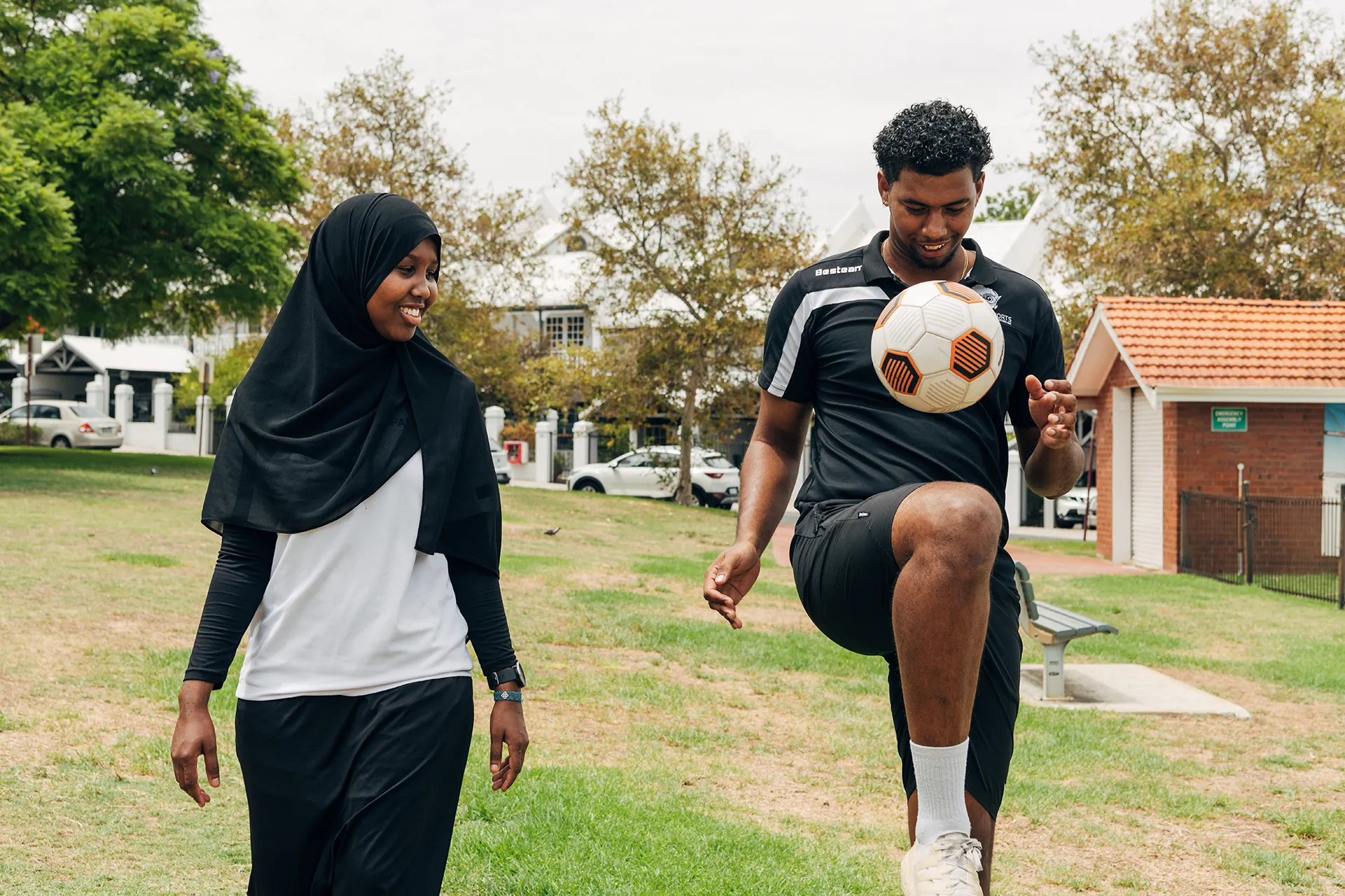 Man playing with soccer ball with lady laughs and watches on